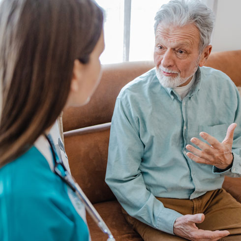Senior man sitting on couch talking to a younger female provider