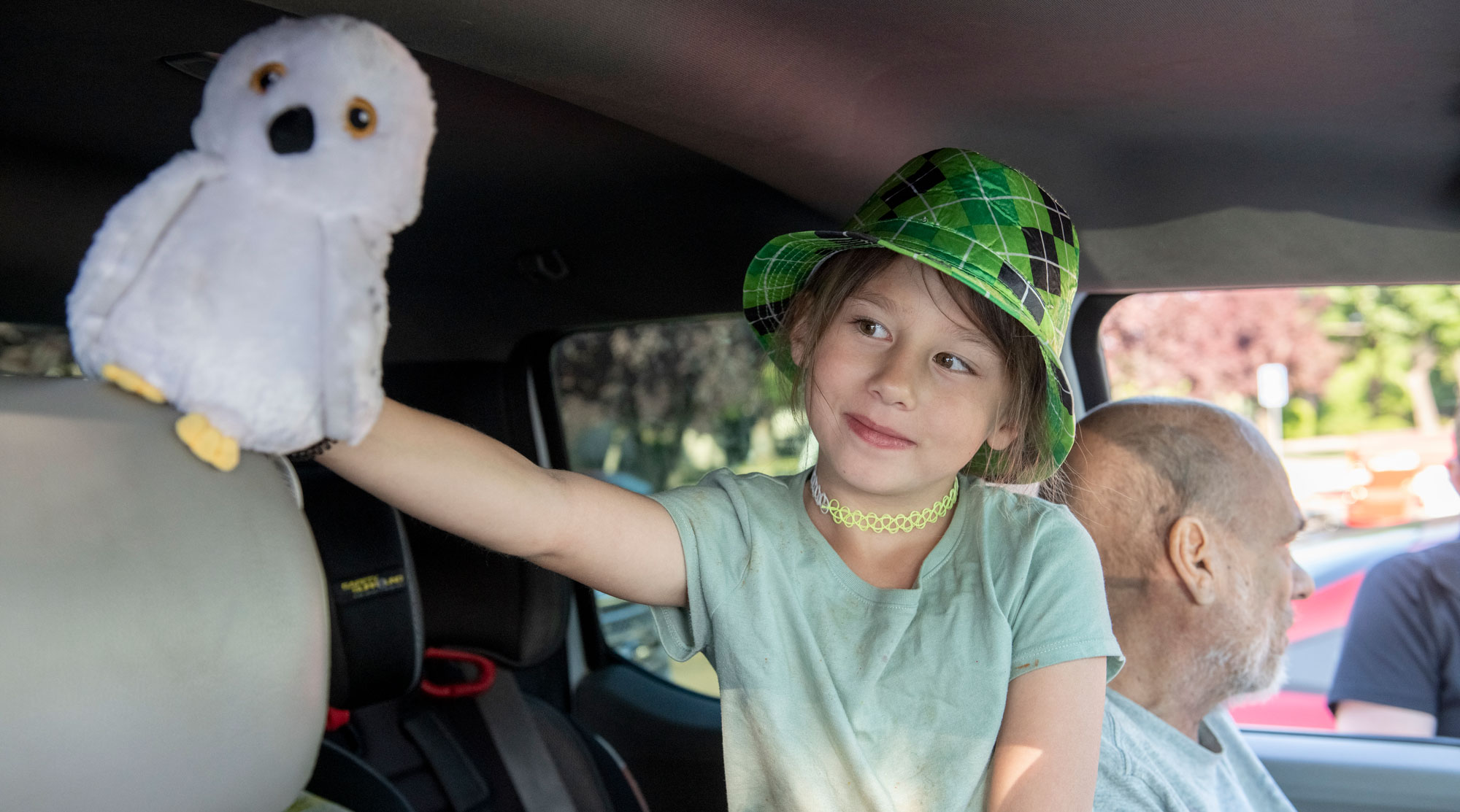 Photo of a little girl holding a stuffed owl in a car.