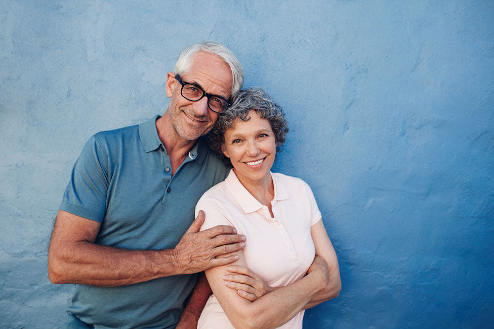 Senior couple with a blue wall behind them