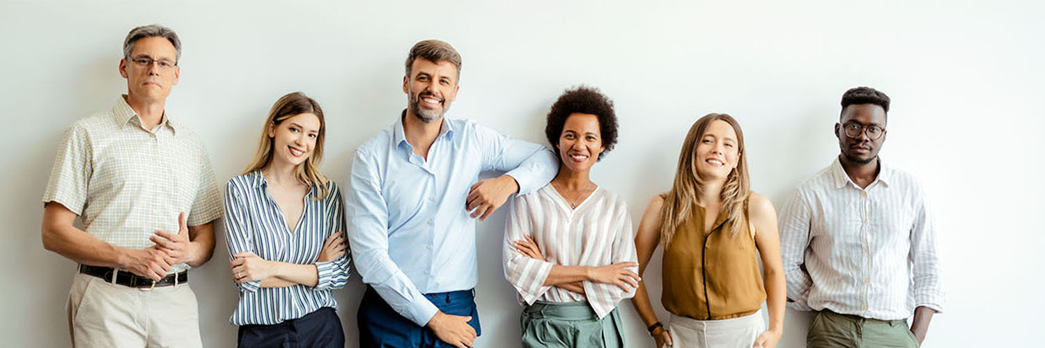 Six adults standing up against a white wall