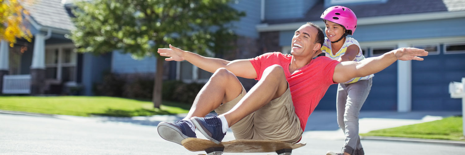 Dad being pushed on skateboard by daughter