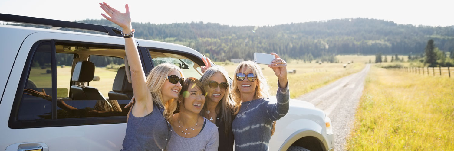 Four women waving at selfie