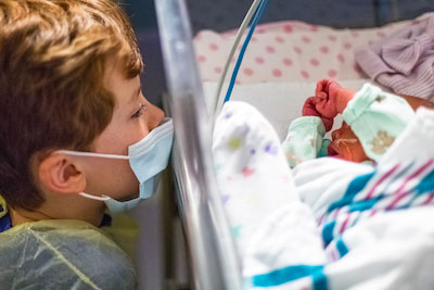 Bigger brother looking at baby in NICU